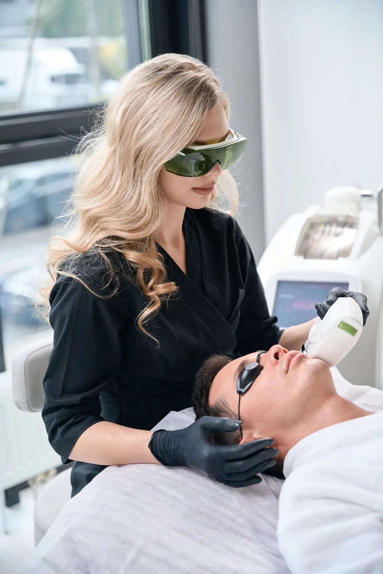 A sleek, white laser treatment device with a green accent panel and ergonomic grip.